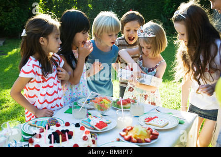 Mädchen Geschenk auf Geburtstagsparty zu öffnen, wie Freunde beobachten Stockfoto