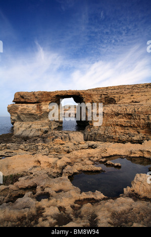 Ein blauer Himmel mit Bauchspeck weiße Wolken hinter das Azure Window, ein Kalkstein-Feature an der Westküste von Gozo Stockfoto