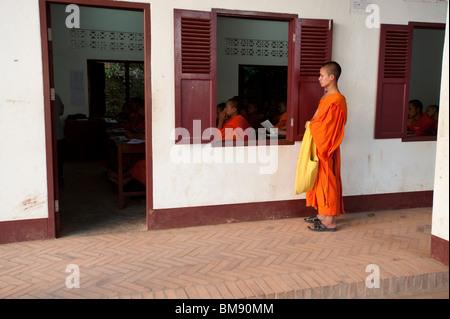 Ein buddhistischer Mönch sieht durch das Fenster einen Tempel Schulraum Stockfoto