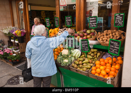 Großbritannien, Cornwall, Launceston, High Street, Kunden im traditionellen Gemüsehändler außerhalb Obst Anzeige Stockfoto