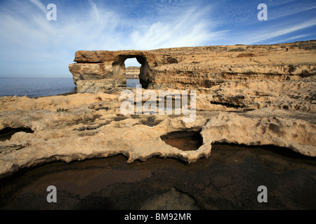 Ein blauer Himmel mit Bauchspeck weiße Wolken hinter das Azure Window, ein Kalkstein-Feature an der Westküste von Gozo Stockfoto