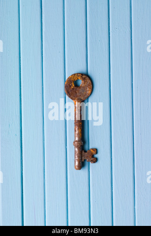 Alten rostigen Skelett Schlüssel auf blauem Untergrund aus Holz Stockfoto
