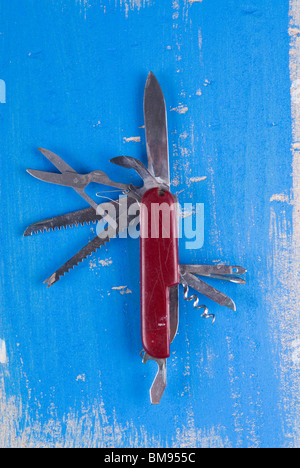 Alte Schweizer Taschenmesser auf einen strukturierten blauen hölzernen Hintergrund Stockfoto