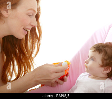 Mutter Fütterung Baby gelbe Löffel weißen Hintergrund Stockfoto