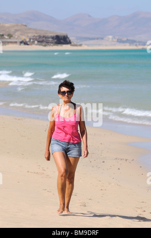 Ältere Frau zu Fuß am Strand Stockfoto