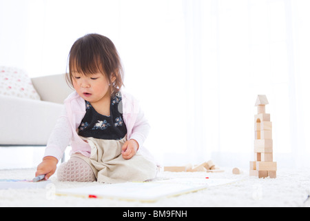 Baby girl Wahl Buntstifte neben Holz- Bausteine Stockfoto