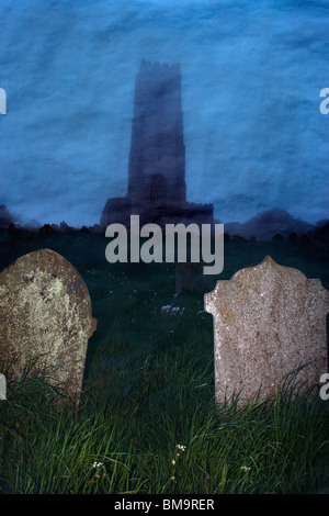 Ein Kirchturm ragt in den Nebel, mit Blick auf einem Friedhof in der Abenddämmerung. Stockfoto