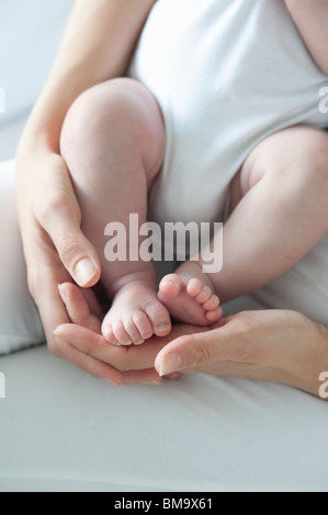 Mutter hält Baby jungen Füße Stockfoto