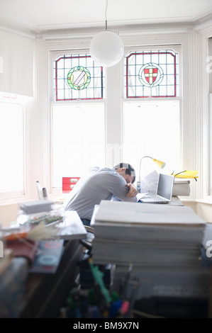 Mitte erwachsener Mann schläft auf seinem Schreibtisch Stockfoto