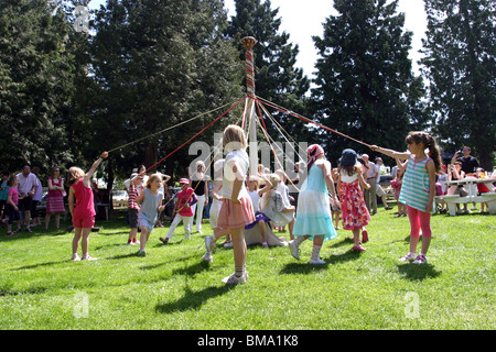 Kinder tanzen den Maibaum auf einem Schulfest Sommer Stockfoto