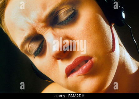 Frau mit extremen Ausdruck auf ihrem Gesicht, tragen von Kopfhörern. Stockfoto