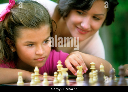 Mama schaut zu, wie Tochter Schach spielt. Stockfoto