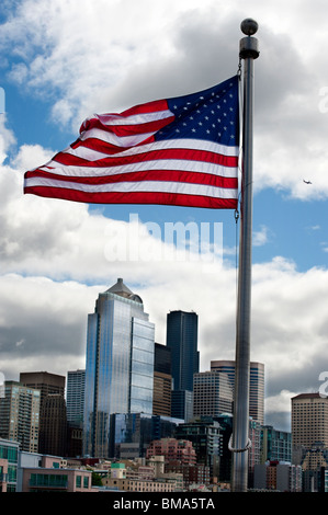 Die amerikanische Flagge Wellen über die Skyline von Seattle, Washington an einem bewölkten Frühlingstag. Gesehen von Pier 66 auf Elliott Bay waterfront Stockfoto