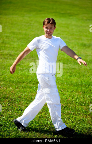 Junger Mann zu Fuß auf dem grünen Rasen. Stockfoto
