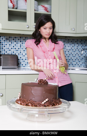 Junge Frau Essen Sellerie, gerade Schokoladenkuchen Stockfoto