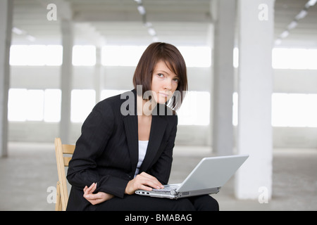 Business-Frau arbeitet am Laptop in leere Lager Stockfoto