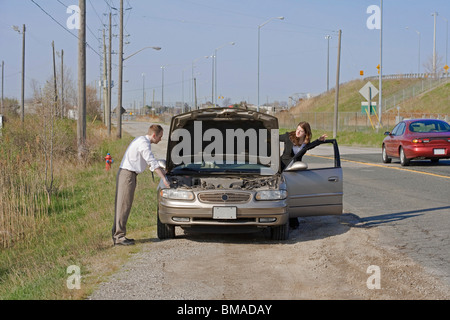 Mann und Frau mit Probleme mit dem Auto auf der Suche unter der Haube Stockfoto