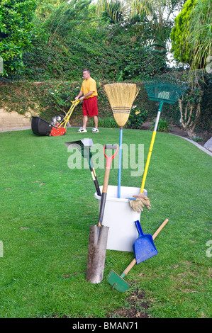 Eine Gardner einen Rasen mäht und bereitet sich auf andere Gartenarbeit durchführen Stockfoto