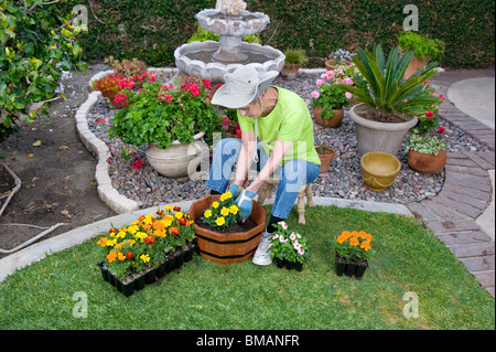Ein Alter Mensch Pflanzen Blumen in einem hölzernen Blumentopf in ihrem Hinterhof. Stockfoto