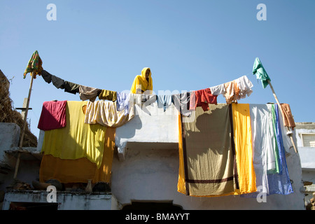 Tücher Trocknen auf Dach und Draht Frau in gelb Sari suchen; halb städtische Siedlung Dilwara; Udaipur; Rajasthan; Indien Stockfoto