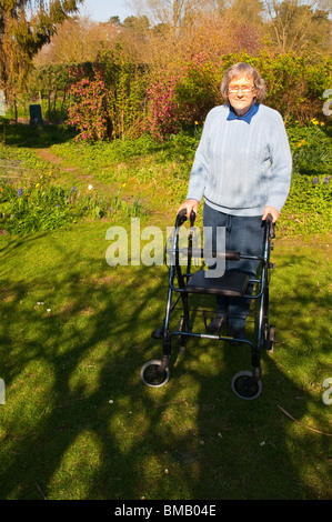 Ein MODEL Release Bild einer älteren Frau mit ihrem Rollator (walking Frame) in einen Bauerngarten in Suffolk, England, Vereinigtes Königreich Stockfoto