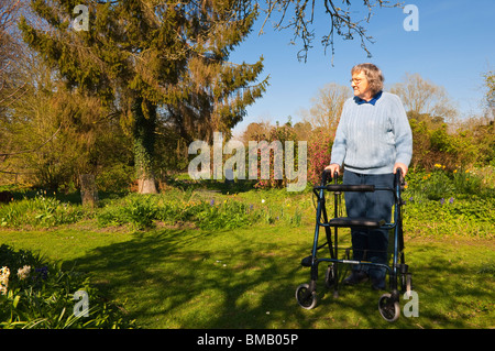 Ein MODEL Release Bild einer älteren Frau mit ihrem Rollator (walking Frame) in einen Bauerngarten in Suffolk, England, Vereinigtes Königreich Stockfoto