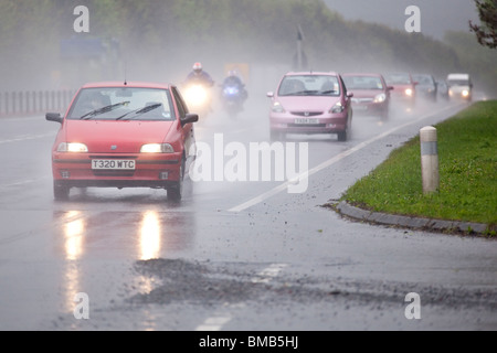 Zweispurige Straße Morgen Feierabendverkehr auf A75 Schlechtwetter Regen Zerstäuberpumpe Motorräder überholen eine Schlange von Autos UK Stockfoto