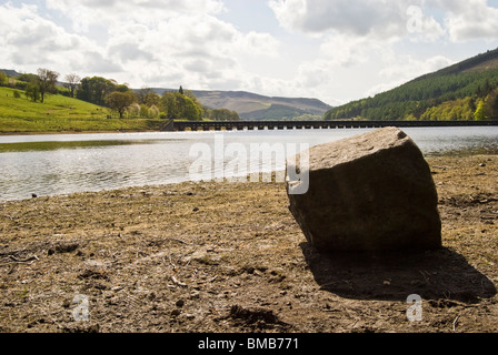 zeigen Sie Ladybower Derwent Reservoir Peak District Derbyshire ausgesetzt Felsbrocken während der Trockenperiode Rohr Linie Viadukt in Ferne an Stockfoto