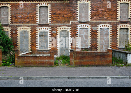 Verlassene Häuser mit Fenstern und Türen in einer innerstädtischen Straße in Belfast zugemauert Stockfoto