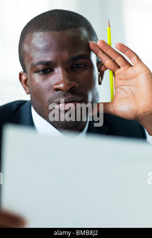 junge Erwachsene afroamerikanischer Geschäftsmann Prüfung Unterlagen drinnen Stockfoto