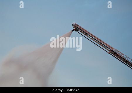 Aus der Ferne kontrolliert Feuer soplo Besprühen mit Wasser von oben ein Feuerwehrauto Schiebeleiter. Platz für Kopie. Stockfoto