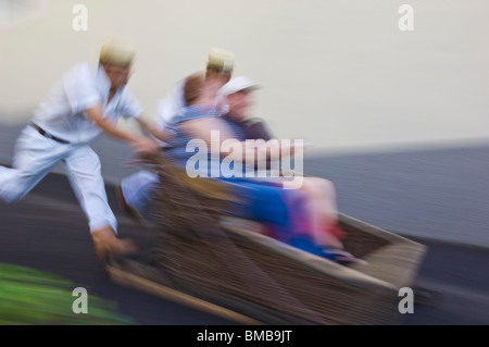 Carrinhos de Monte, mit Touristen fahren in Wicker Schlitten Monte oberhalb Funchal, Madeira, Portugal, EU, Europa Stockfoto