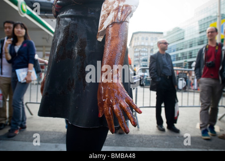 Demonstranten verschütten flüssiges Öl vertritt über sich selbst vor einer BP-Tankstelle in Soho in New York Stockfoto