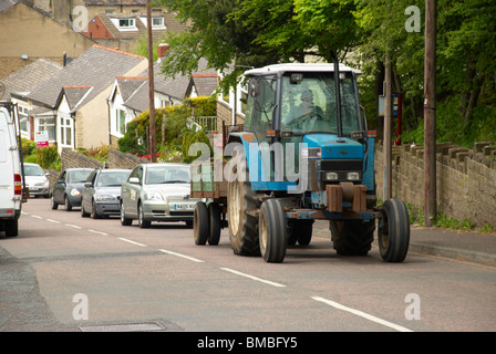 Traktor auf einem Hügel mit Verkehr Tailing dahinter zurück. Stockfoto