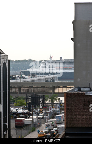 Cunard-Flaggschiff-Luxusliner Queen Mary 2 gesehen zwischen Gebäuden in New York Hells Kitchen segelt hinunter die Hudson bei Sonnenuntergang Stockfoto