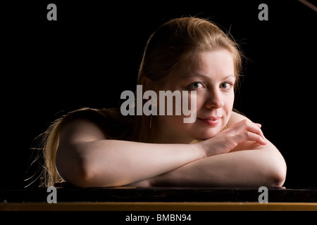 schöne nachdenkliche Mädchen legte die Hände auf den Deckel des Klaviers Stockfoto