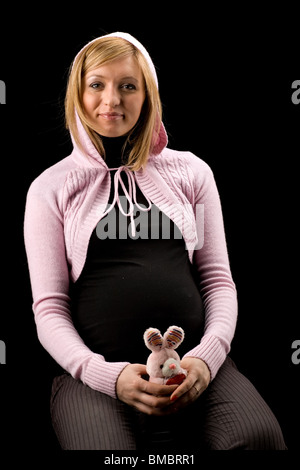 schöne schwangere Frau in rosa Jacke, auf schwarzem Hintergrund isoliert Stockfoto