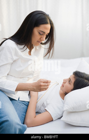 Frau, die ihre Tochter Temperatur prüfen Stockfoto