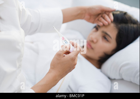 Frau, die ihre Tochter Temperatur prüfen Stockfoto