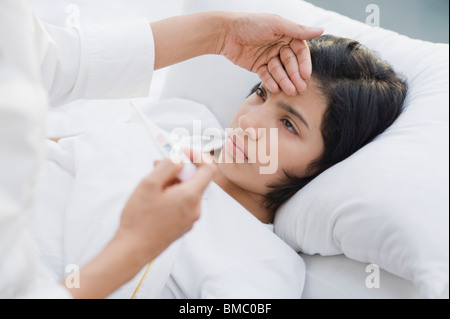 Frau, die ihre Tochter Temperatur prüfen Stockfoto