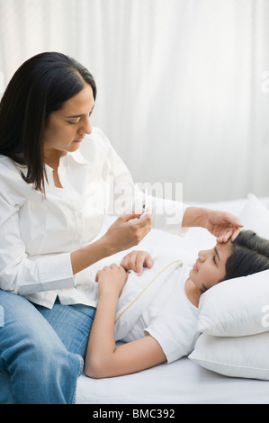 Frau, die ihre Tochter Temperatur prüfen Stockfoto
