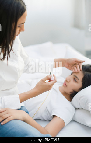 Frau, die ihre Tochter Temperatur prüfen Stockfoto