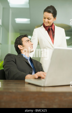 Geschäftsmann, arbeiten auf einem Laptop mit seinem Kollegen neben ihm stehenden Stockfoto