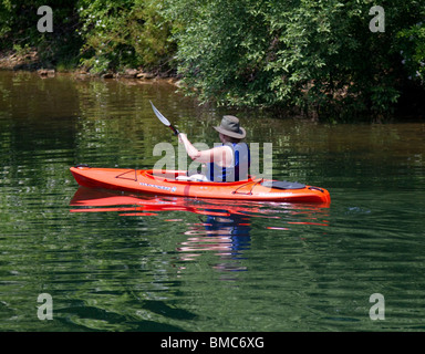 Eine Frau in einem orange Kajak. Paddeln entlang der Küste bei Merrill Creek Reservoir, New Jersey. Stockfoto