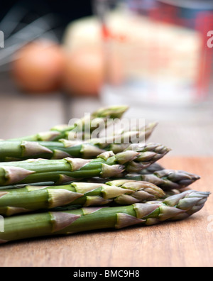 Frischer Spargel auf ein Schneidbrett aus Holz, mit Zutaten für die Sauce Hollandaise im Hintergrund angelegt Stockfoto