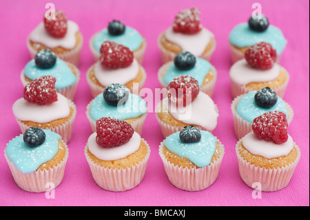 Bunte Heidelbeere und Himbeere Mini Frucht Muffins auf einem rosa Hintergrund Stockfoto