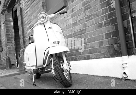 Weißes 60er Jahre Retro-Scooter Vespa, Lambretta, lässig auf der Straße geparkt Stockfoto