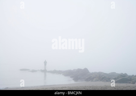 Mann auf Felsen im Nebel Stockfoto