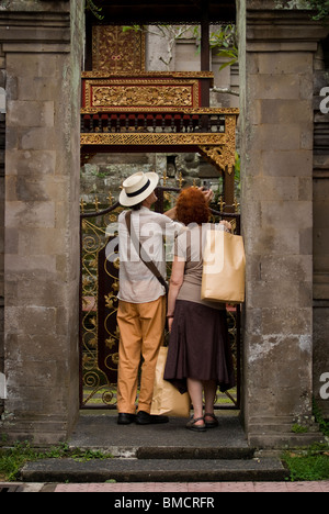 Touristen halten, um ein Foto in einem hinduistischen Tempel entlang der Jalan Raya im Kulturzentrum und Dorf von Ubud, Bali zu machen. Stockfoto