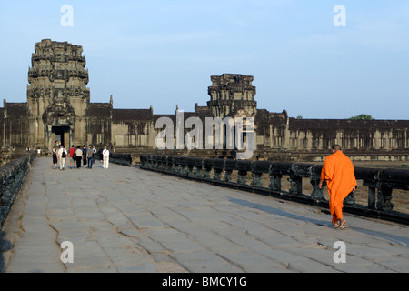 Ein Mönch zu Fuß auf den Naga-Damm in Richtung der westlichen Gopura, Angkor Wat, Kambodscha. Stockfoto